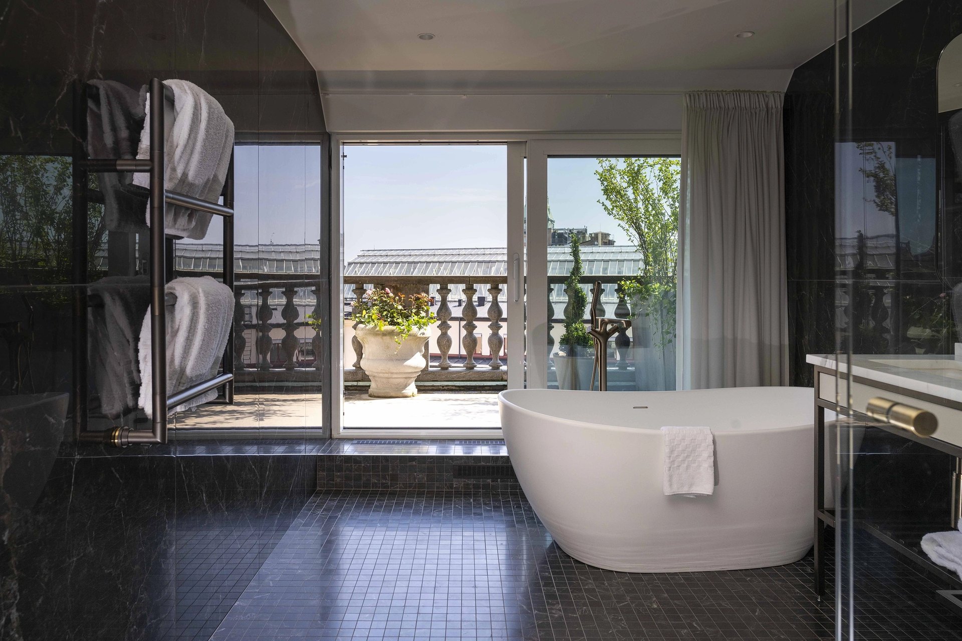 A marble bathroom at Bank Hotel, with a freestanding bath opening onto a rooftop terrace