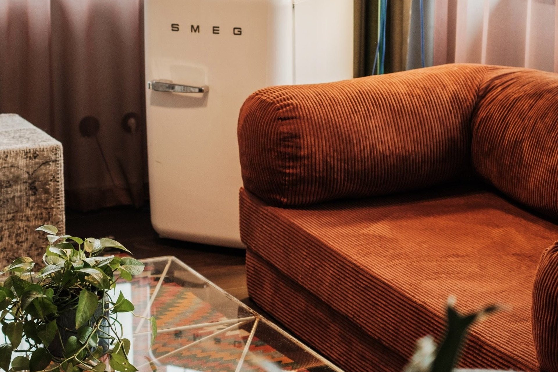 A corduroy sofa, retro fridge and green lamp in a Hobo room