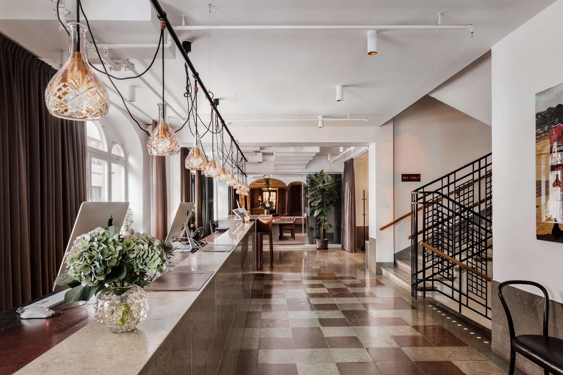 The long lobby of Miss Clara, crystal pendant lamps over a stone counter and a chequered floor