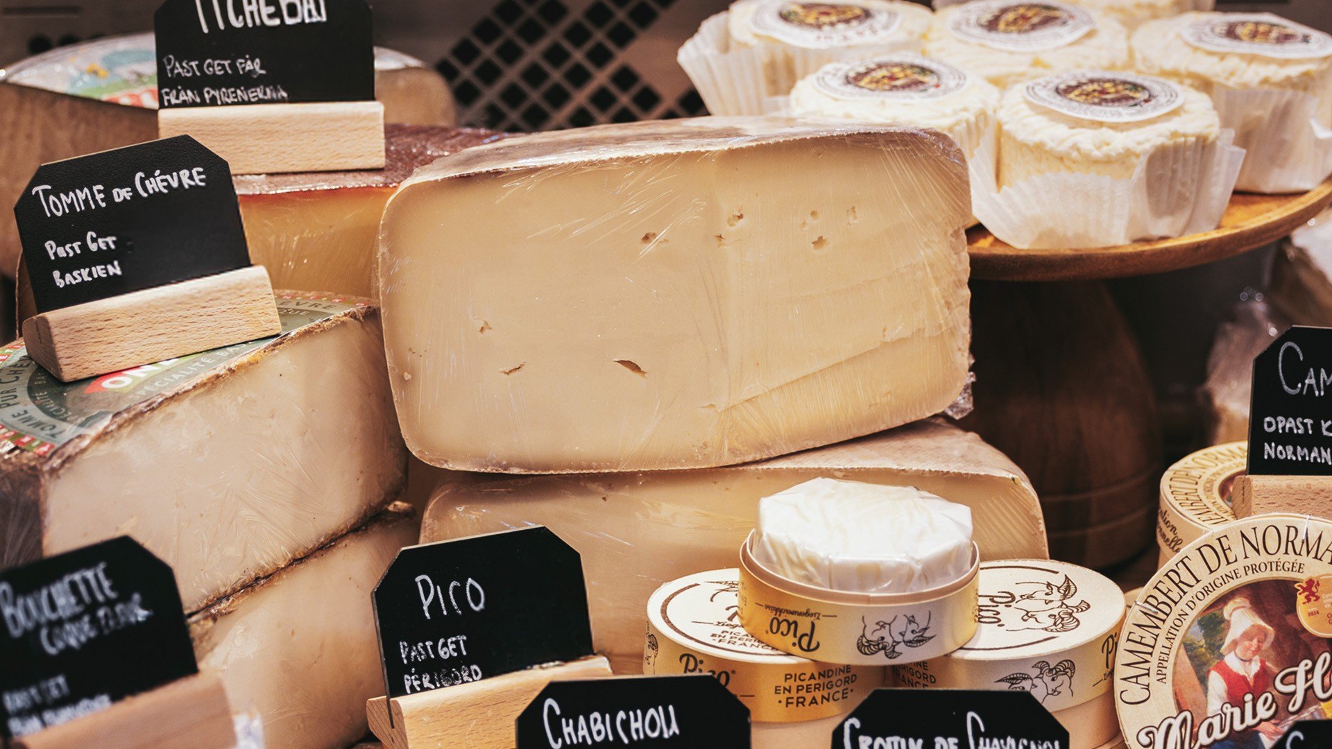 Cheeses with chalkboard labels on a counter at Östermalms Saluhall